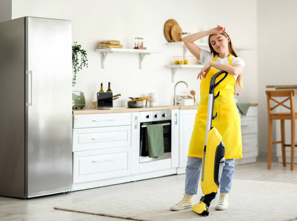Mujer joven con aspiradora en la cocina - Foto, imagen