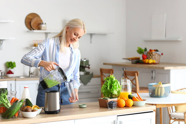 Felnőtt nő öntött egészséges smoothie üvegbe a konyhában - Fotó, kép