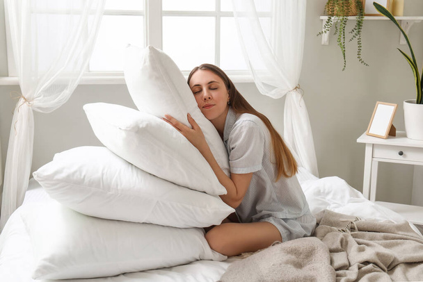 Aamulla kaunis nuori nainen monia pehmeitä tyynyjä makuuhuoneessa - Valokuva, kuva