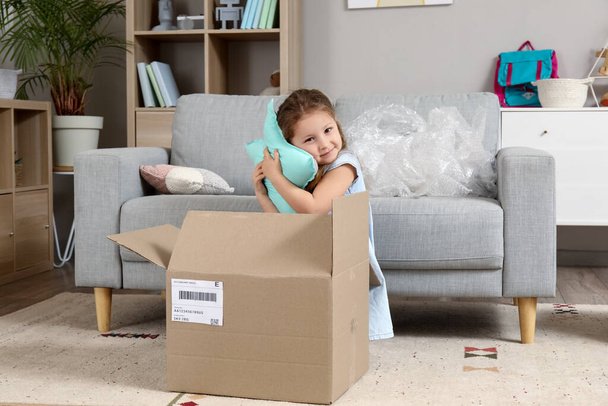 Cute little girl unpacking parcel with pillow at home - Photo, Image