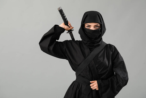 Ninja femenino con espada sobre fondo gris - Foto, Imagen