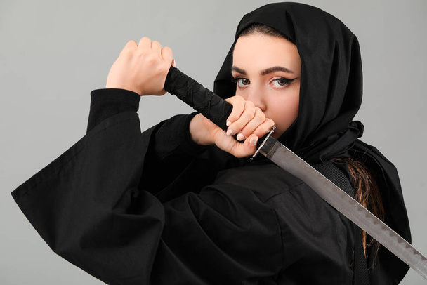 Female ninja with sword on grey background - Photo, Image