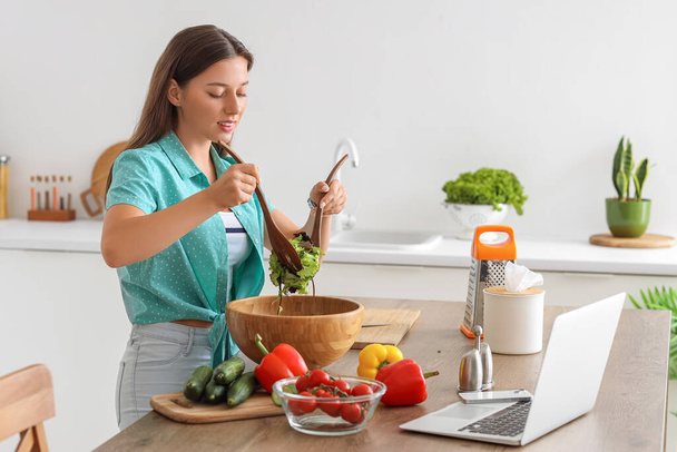 Jonge vrouw bereidt groentesalade in de keuken - Foto, afbeelding