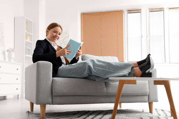Νεαρή επιχειρηματίας διαβάζει βιβλίο στο σπίτι μετά από μακρά εργάσιμη ημέρα - Φωτογραφία, εικόνα