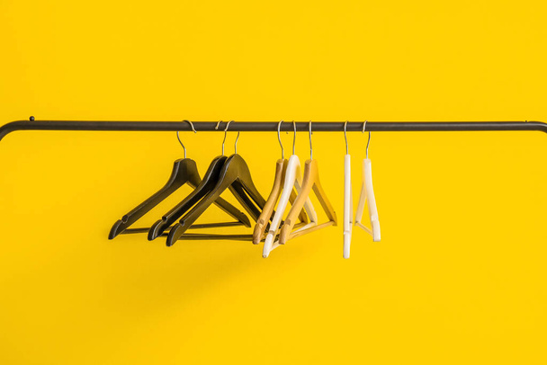 Стелаж з дерев'яними вішаками для одягу на жовтому тлі - Фото, зображення