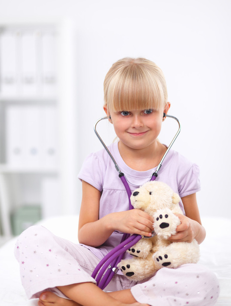 Little girl is examining her teddy bear using stethoscope - Φωτογραφία, εικόνα