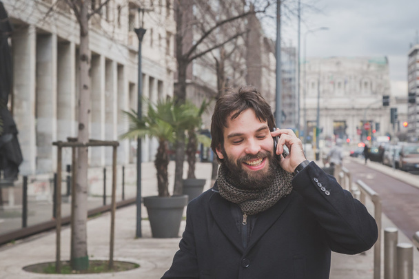 Fiatal jóképű szakállas ember beszél telefonon - Fotó, kép
