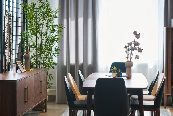 Posto di lavoro composto da tavolo e gruppo di sedie per colletti bianchi in ampia sala riunioni o spazio aperto con piante domestiche verdi - Foto, immagini