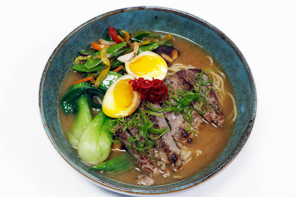 asian food speciality ramen noodle soup with beef strips, poached eggs, bok choi and summer vegetables in a bowl - Photo, image