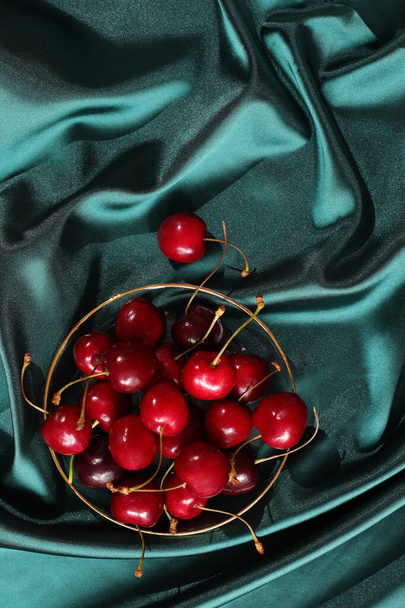 Baya roja fresca de cereza sobre fondo sedoso verde esmeralda - Foto, Imagen
