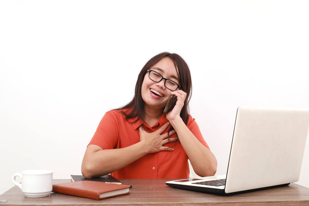 Zwolniona młoda azjatycka przedsiębiorczyni trzymająca klatkę piersiową podczas rozmowy przez telefon. Izolacja - Zdjęcie, obraz