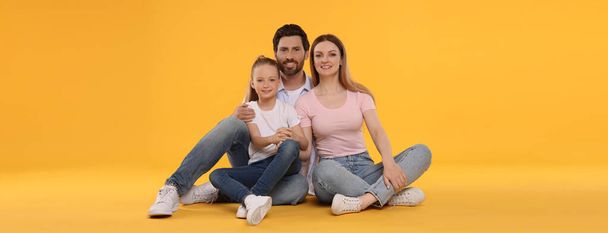 Happy family with child on orange background. Banner design - Фото, изображение
