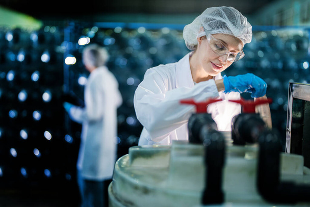 Fabrika işçisi endüstriyel fabrikadaki depoda su şişelerini kontrol ediyor. İçki üretim hattında veri kaydeden kadın işçi.. - Fotoğraf, Görsel