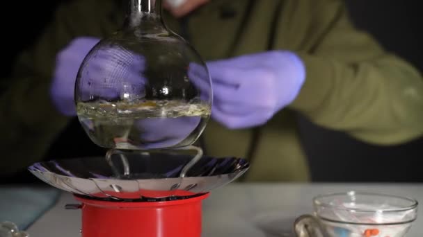 Chemik v podzemní laboratoři vaří drogu ve skleněné baňce na plynovém hořáku - Záběry, video