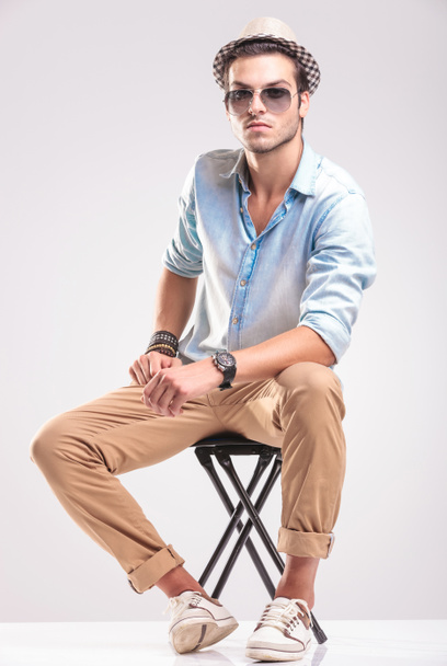 Hombre de moda sentado apoyando sus manos en su pierna
 - Foto, imagen