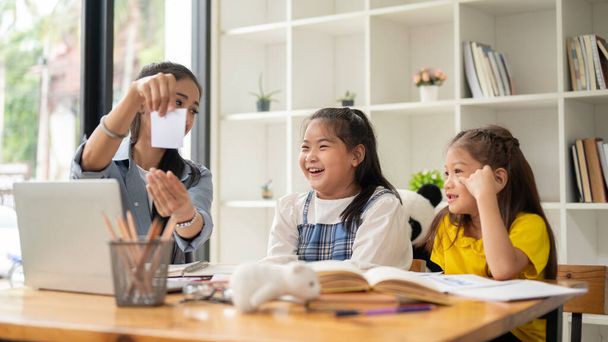 Two adorable young Asian girls are enjoying studying English with a teacher in a private class at home. Education concept - Photo, Image