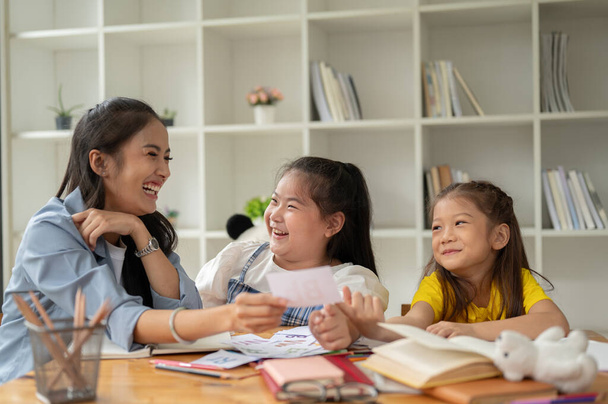 Dos niñas asiáticas adorables se ríen y disfrutan estudiando tarjetas de vocabulario inglés con un profesor privado en casa. preescolar, jardín de infantes, escuela primaria - Foto, Imagen
