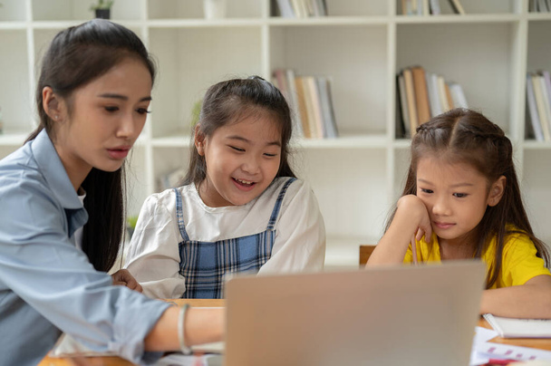 Kaksi onnellista ja söpöä nuorta aasialaista tyttöä opiskelee yksityisen opettajan kanssa kotona, oppimalla läppäriä yhdessä.. - Valokuva, kuva