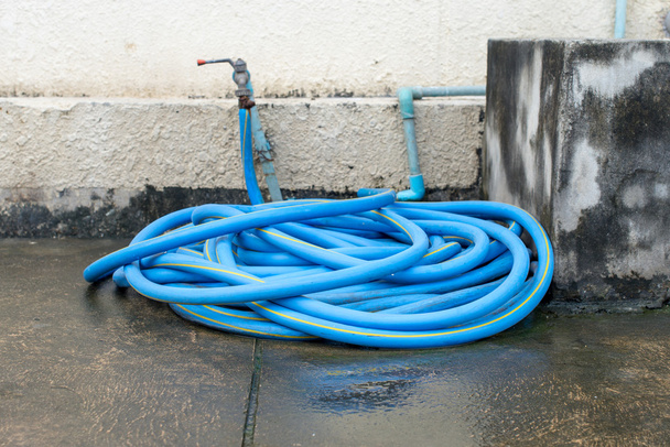 Резиновая трубка подключена к старому водопроводному крану на полу
 - Фото, изображение