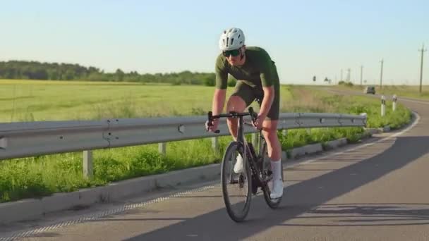 Young sports competitor boosting power on racing bike while cycling out of saddle during outdoor training. Efficient athlete getting most out of standing before returning to seated position on ride. - Footage, Video