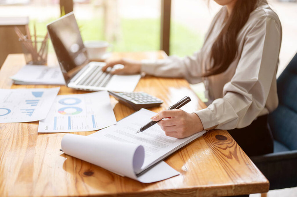 Обрезанный образ профессиональной азиатской бизнесвумен или бухгалтера фокусируется на ее работе за ее столом в офисе. - Фото, изображение
