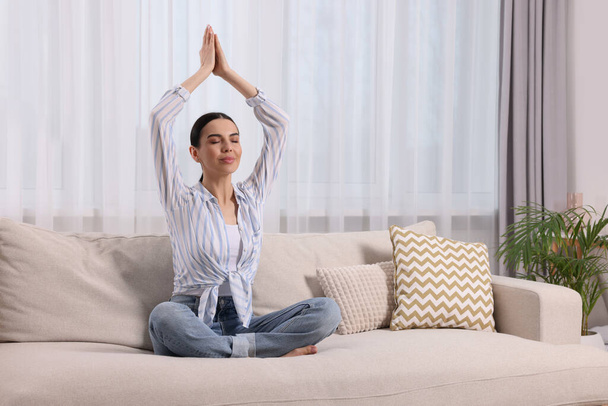 Woman meditating on sofa at home, space for text - Photo, Image