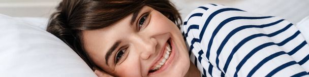 Happy beautiful girl smiling while lying in bed after sleep at home - Foto, Bild