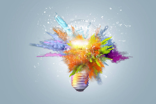 Creative concept light bulb explodes with colorful water colors on a light blue background. Think different, creative idea. Productivity and creativity - Photo, Image