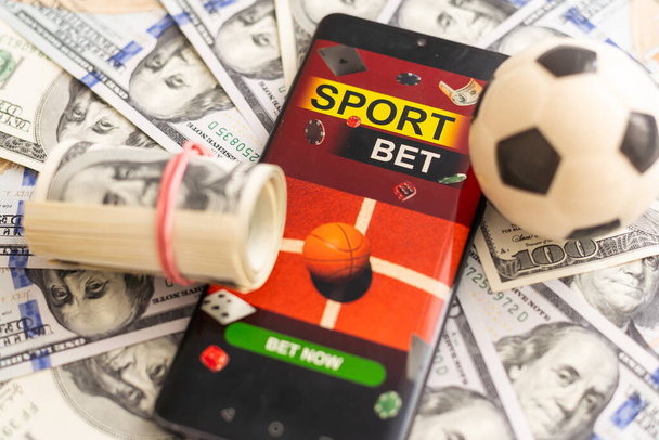 Smartfon z hazardem aplikacja mobilna i piłka nożna z zbliżeniem pieniędzy. Koncepcja sportu i zakładów. Wysokiej jakości zdjęcie - Zdjęcie, obraz