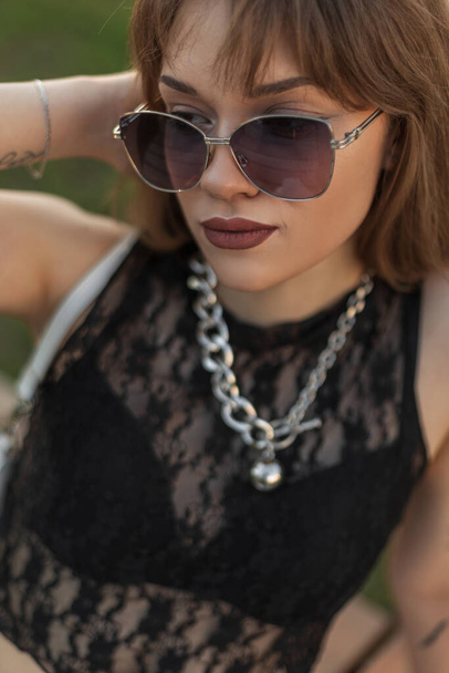Klasik güneş gözlüklü, seksi, dantelli siyah bluzlu güzel bir kadının şehir modası portresi. - Fotoğraf, Görsel