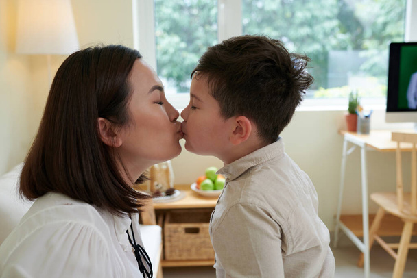 Little boy kissing mother on lips when they are playing in nursery - Fotografie, Obrázek