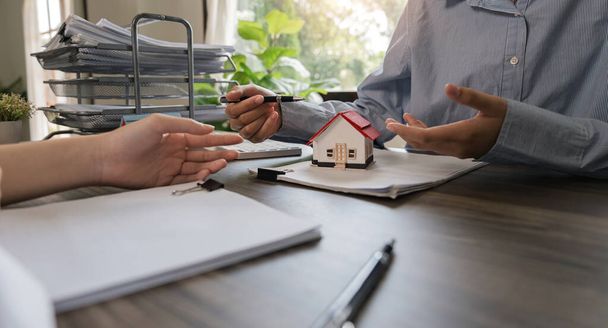 Les acheteurs négocient avec les agents immobiliers au sujet de la location ou de l'achat d'une maison au bureau. - Photo, image