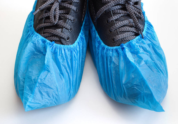 Sapatilhas nas botas. Cobertura médica azul para visita ao hospital. - Foto, Imagem