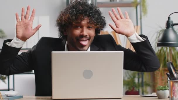 Indian businessman hiding behind laptop computer, making funny face, fooling around, putting his tongue out remote working disrespecting someone at office desk workplace. Professional freelancer man - Filmagem, Vídeo