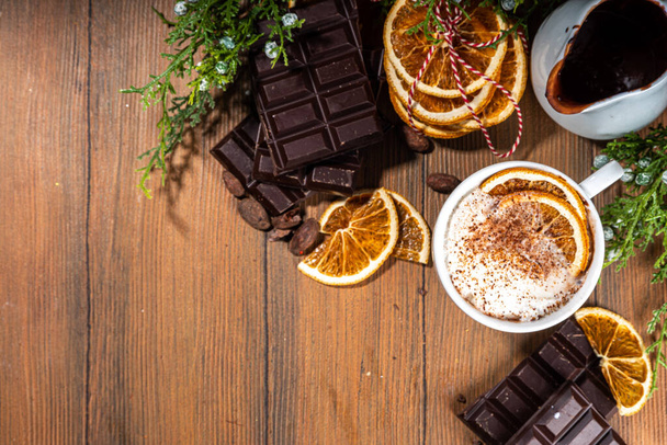 Orange heißes Kakaogetränk. Hausgemachte Winterweihnacht dunkle würzige heiße Schokolade mit getrockneten Orangen, mit Schokolade und Orangenscheiben auf gemütlichen hölzernen Hintergrund  - Foto, Bild