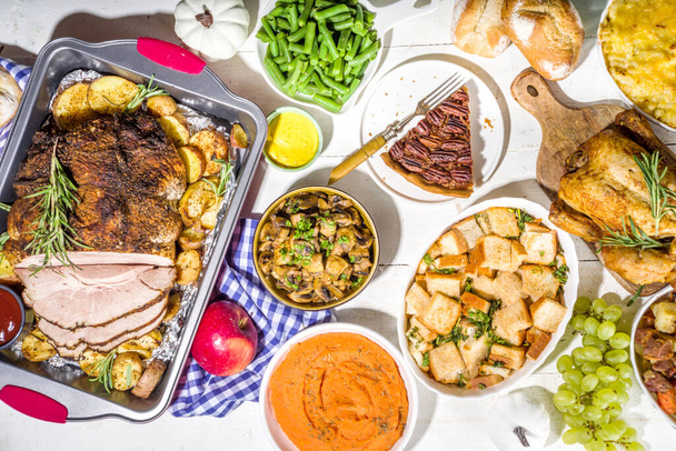 Kiitospäivän ruokapöytä uudella perinteisellä kiitospäivän ruoalla kanaa, perunamuusia, vihreitä papuja, pekaanipähkinäpiirakkaa, paistettua kinkkuporsasta, makaronia ja juustoa, täyte, moderni kova aurinkoinen valo flatlay - Valokuva, kuva