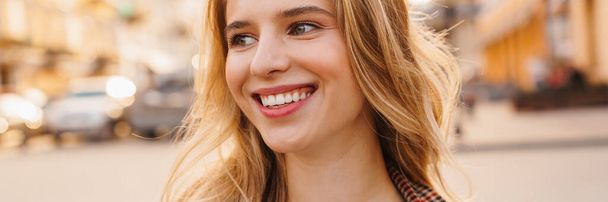 Close up of a smiling blonde young woman walking on a street - Fotografie, Obrázek