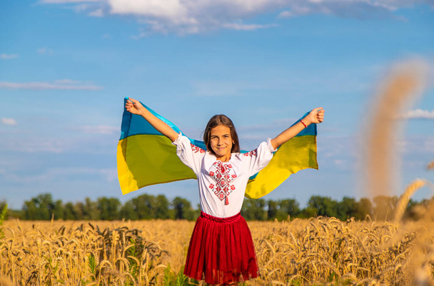 Bambino in un campo di grano con la bandiera dell'Ucraina. Concentrazione selettiva. Ragazzo.. - Foto, immagini