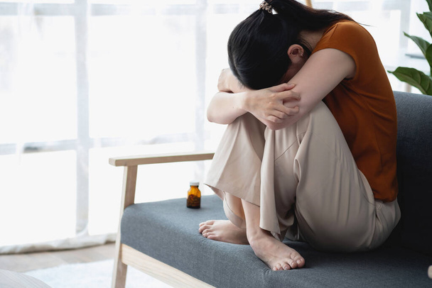 молодая женщина, сидящая на диване с большим количеством таблеток Депрессивная женщина хочет убить себя передозировкой наркотиков, концепция депрессии - Фото, изображение