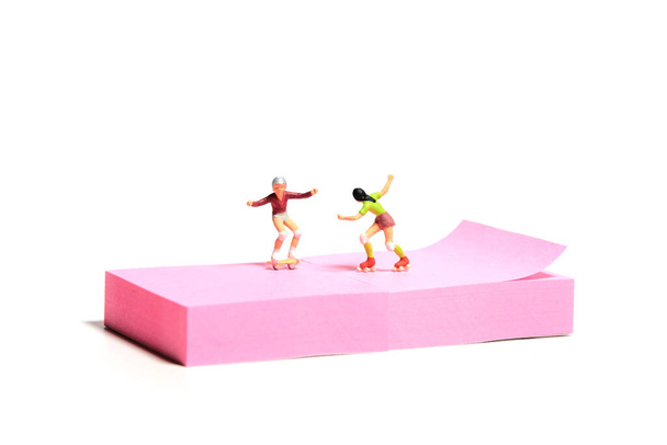 Creative miniature people toy figure photography. Sticky notes installation. A girl roller skater playing at skate park. Isolated on white background. Image photo - Photo, Image