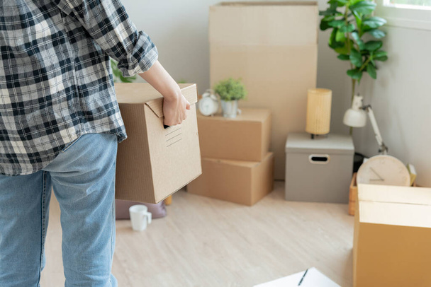 Moving house, relocation. Woman hold carton box contain equipment for new condominium, inside the room was a cardboard box containing personal belongings and furniture. move in the apartment - Photo, Image