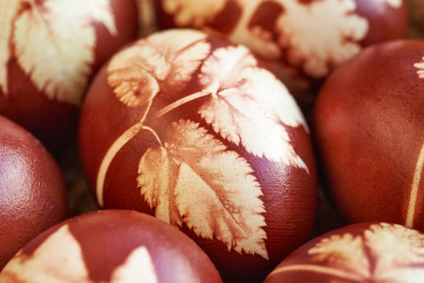 Kahverengi Paskalya yumurtalarının yakın çekimleri soğan kabuklarıyla boyanmış ve yaprak desenleri var. - Fotoğraf, Görsel
