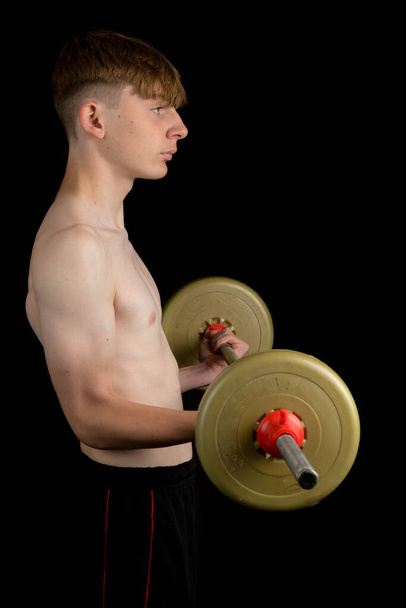 Portrait of a sporty shirtless teenage boy exercising with a barbell - Foto, immagini
