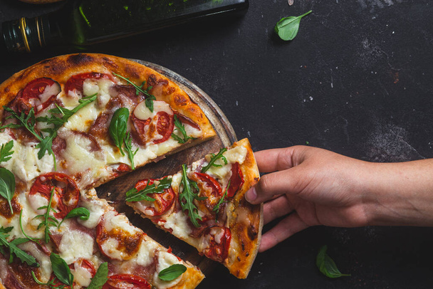 Pizza mit Schinken, Tomaten und Mozzarella auf dunklem Hintergrund - Foto, Bild