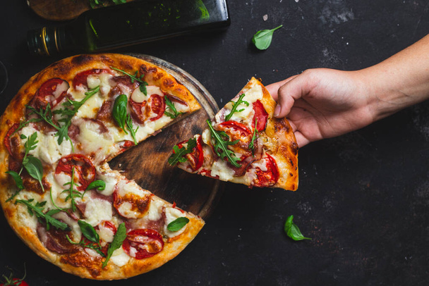 Pizza au jambon, tomates et mozzarella sur fond sombre - Photo, image