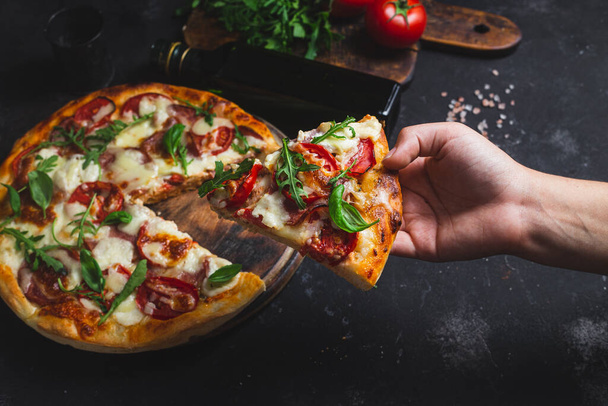 Пицца с ветчиной, помидорами и моцареллой на тёмном фоне - Фото, изображение