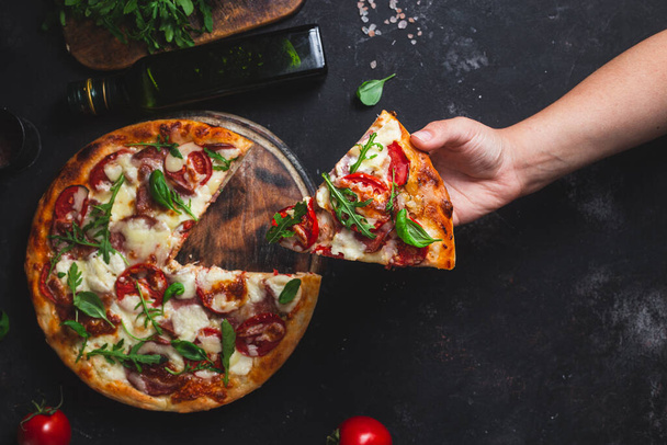 Pizza with ham,tomatoes and mozzarella on a dark background - Photo, Image