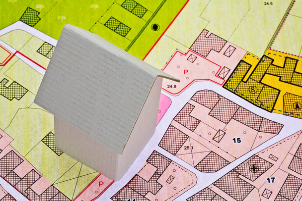 Képzeletbeli kataszteri térkép és általános városi terv épületekkel, földterülettel és városi úti célok megjelölésével - ingatlan koncepció kartondobozzal - Fotó, kép