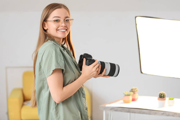 Молода жінка-фотограф з професійною камерою в студії
 - Фото, зображення