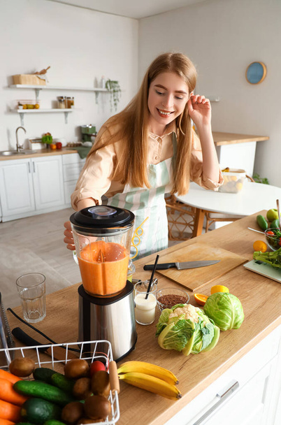 Молодая женщина делает здоровый смузи с блендером на кухне - Фото, изображение